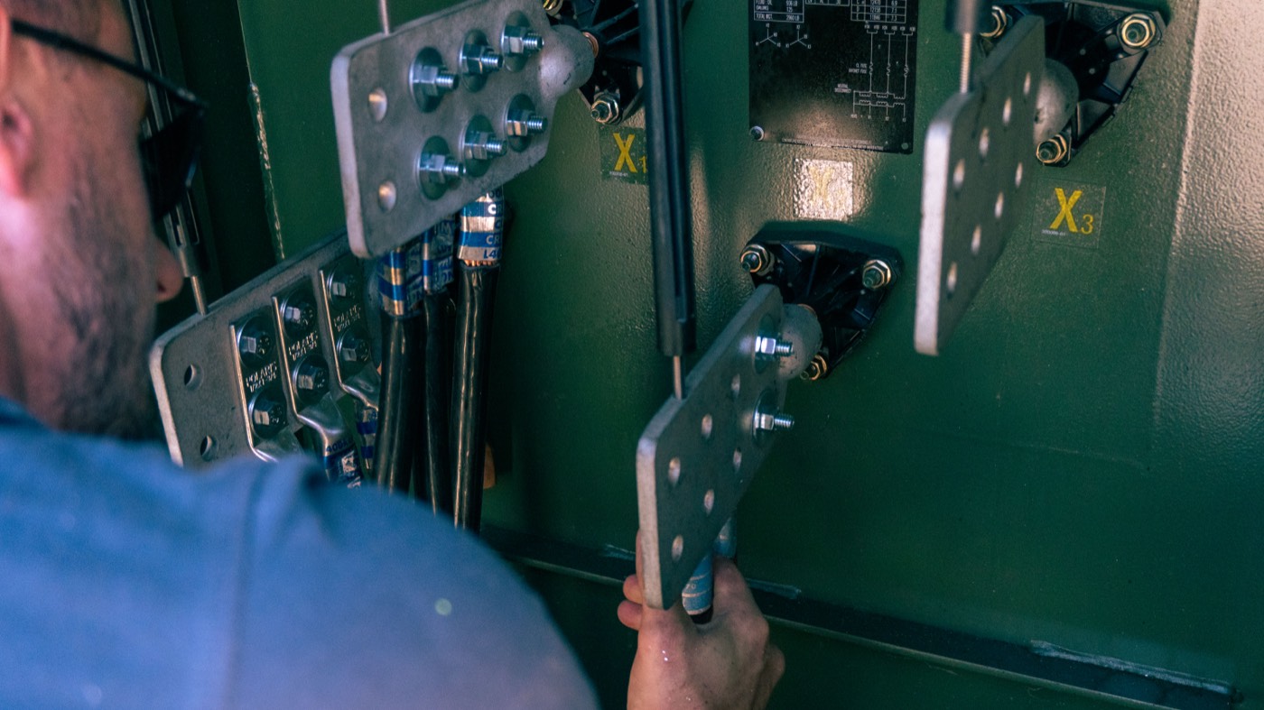 Electrician working inside switchgear cabinet